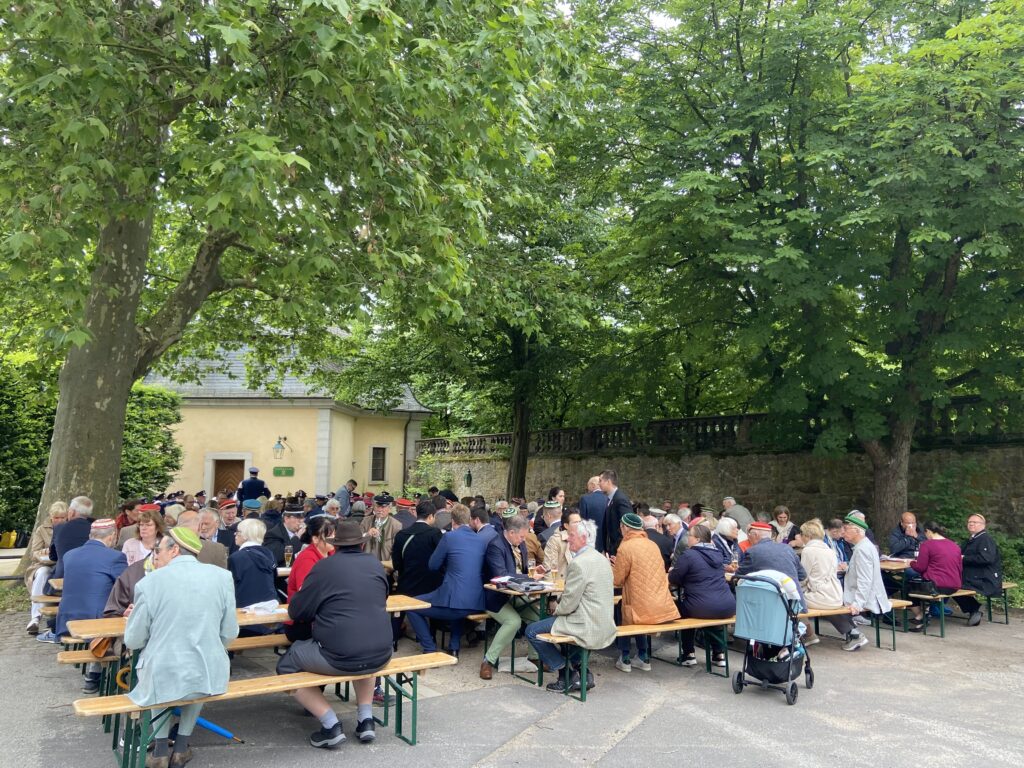 Corona auf dem Bürgerfrühschoppen 2026. Menschen auf Bierbänken vor der Organgerie.